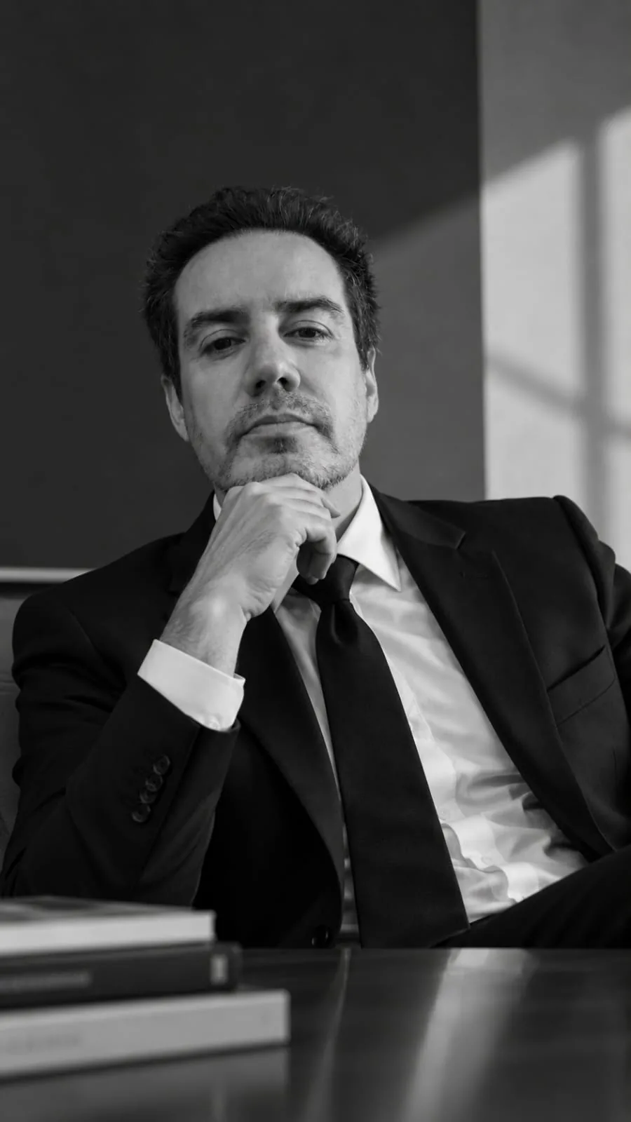 Edson Noyola de traje, sentado a la mesa de trabajo, en blanco y negro