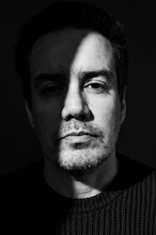 Retrato en blanco y negro de Edson Noyola, la sombra partiendo el rostro
